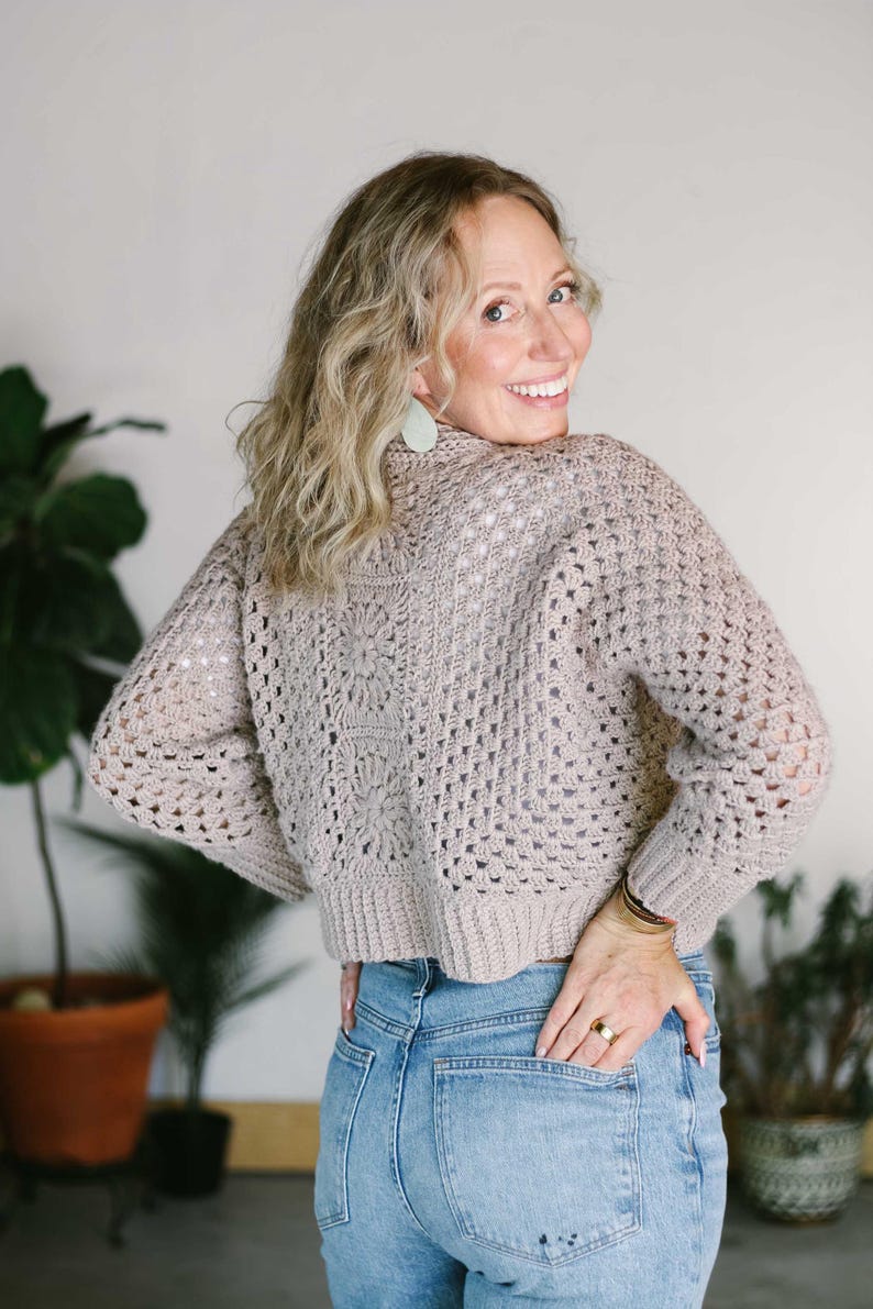 A granny stitch cardigan worn by a woman paired with denim jeans.