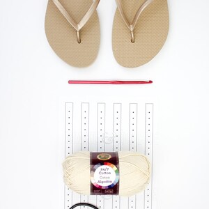 A pair of beige slippers, a crochet hook, a yarn skein, a pair of scissors, and a printable ruler.