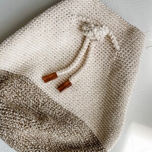A crochet mini backpack with a drawstring enclosure.