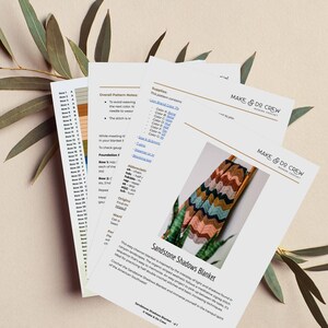 May include: A crochet pattern for a colorful chevron blanket called the Sandstone Shadows Blanket. The pattern is inspired by the interplay of light and shadows found in canyon landscapes. The pattern includes instructions for creating a meditative zigzag stitch sequence.