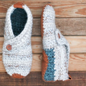 A pair of white warm crochet slippers with leather soles.