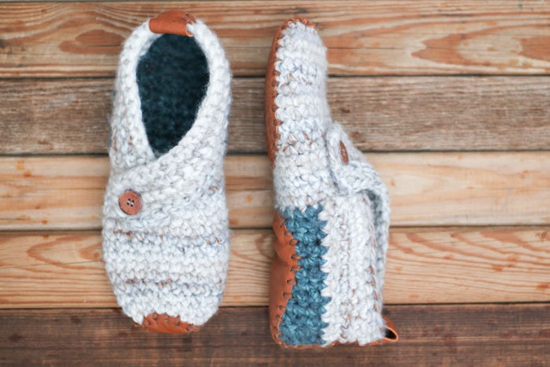 A pair of white warm crochet slippers with leather soles.