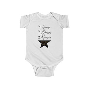 Pode incluir: Macac&atilde;o branco para beb&ecirc; com texto preto que diz "Young, Scrappy, Hungry" e uma estrela preta com texto dourado que diz "Just Like My Country".