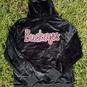 May include: Black velvet hooded sweatshirt with a red rhinestone "Buckeyes" design on the back.