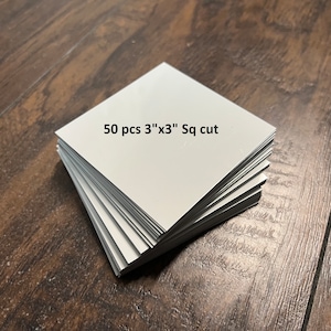 May include: A stack of 50 white, 3 inch by 3 inch square cut pieces of material.