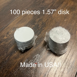 May include: Two stacks of 100 white, round, 1.57 inch diameter discs, wrapped in clear plastic, on a wood surface. The text "100 pieces 1.57" disk" is above the stacks and "Made in USA!" is below the stacks.