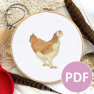 May include: A cross-stitch pattern of a brown and white chicken with a red comb, displayed in a round wooden embroidery hoop. The pattern is labelled "PDF" in a pink circle.