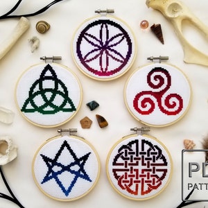 Può includere: Cinque motivi di ricamo in cerchio con diversi disegni di nodi celtici. Ogni motivo presenta un gradiente di colori, tra cui rosso, verde, blu e nero. I cerchi sono in legno e hanno una finitura naturale. Il testo "PDF PATTERN" è visibile nell'angolo in basso a destra dell'immagine.