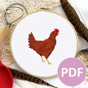 May include: A cross-stitch pattern of a brown chicken with a red comb and wattle. The pattern is displayed in a wooden embroidery hoop on a white background.