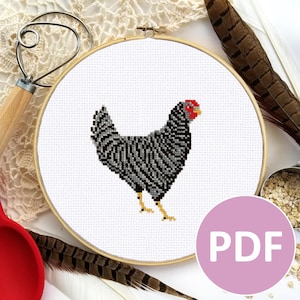 May include: A cross-stitch pattern of a black and white barred Plymouth Rock chicken in a wooden embroidery hoop. The pattern is available as a PDF download.