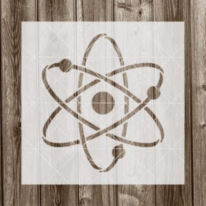 May include: A white stencil of an atom with a nucleus and orbiting electrons. The stencil is on a wood background.
