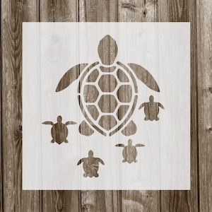 May include: A white stencil of a large sea turtle with four smaller sea turtles surrounding it. The stencil is on a wood background.