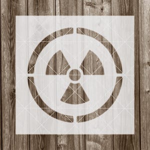 May include: A white stencil of a radiation symbol, also known as the trefoil symbol, on a wood background.