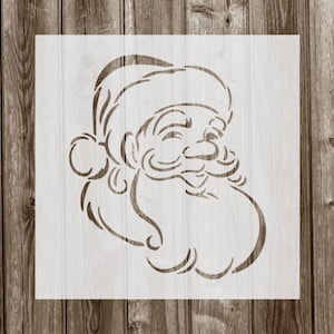 May include: A white stencil of Santa Claus's face with a beard and a hat. The stencil is on a wood background.