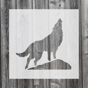 May include: A white stencil of a howling wolf on a rock, set against a weathered, gray wooden background. The wolf is depicted in profile, with its head raised and mouth open. The design is simple and bold.