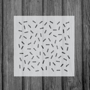 May include: A white stencil with a black geometric pattern of short lines and dashes. The pattern is reminiscent of confetti or sprinkles.