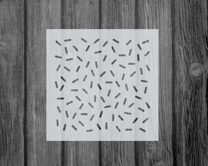 May include: A white stencil with a black geometric pattern of short lines and dashes. The pattern is reminiscent of confetti or sprinkles.