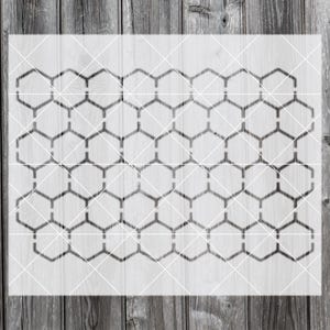 Puede incluir: Un esténcil con un patrón de panal. El diseño consiste en hexágonos interconectados, creando un motivo geométrico repetitivo. El esténcil es de color gris oscuro y está sobre un fondo claro.