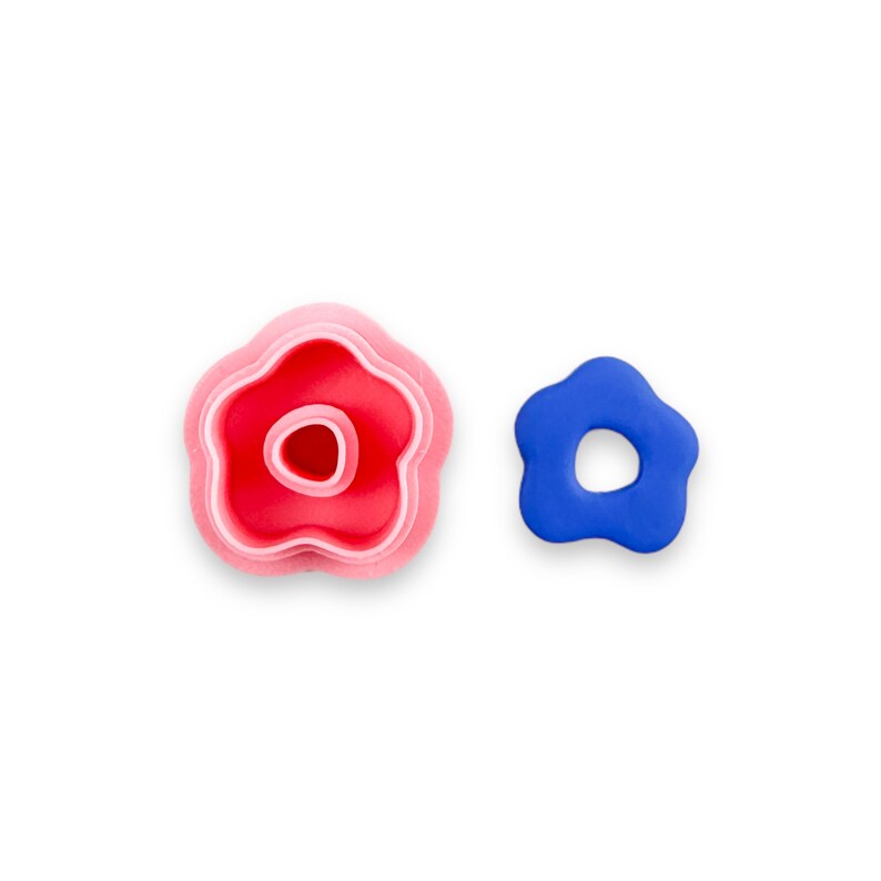 May include: Two flower-shaped cookie cutters, one pink and one blue. The pink cutter is layered, with three different sizes of flower shapes.
