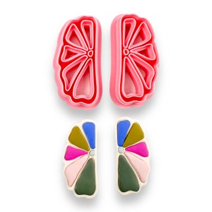 May include: Two pairs of earrings, one pair is pink and the other is multi-colored. The pink pair is a simple flower shape, while the multi-colored pair is a more intricate design with pink, blue, green, and gold accents.