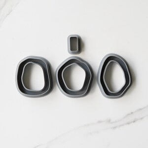 May include: Set of four gray plastic cookie cutters shaped like irregular circles and a rectangle.