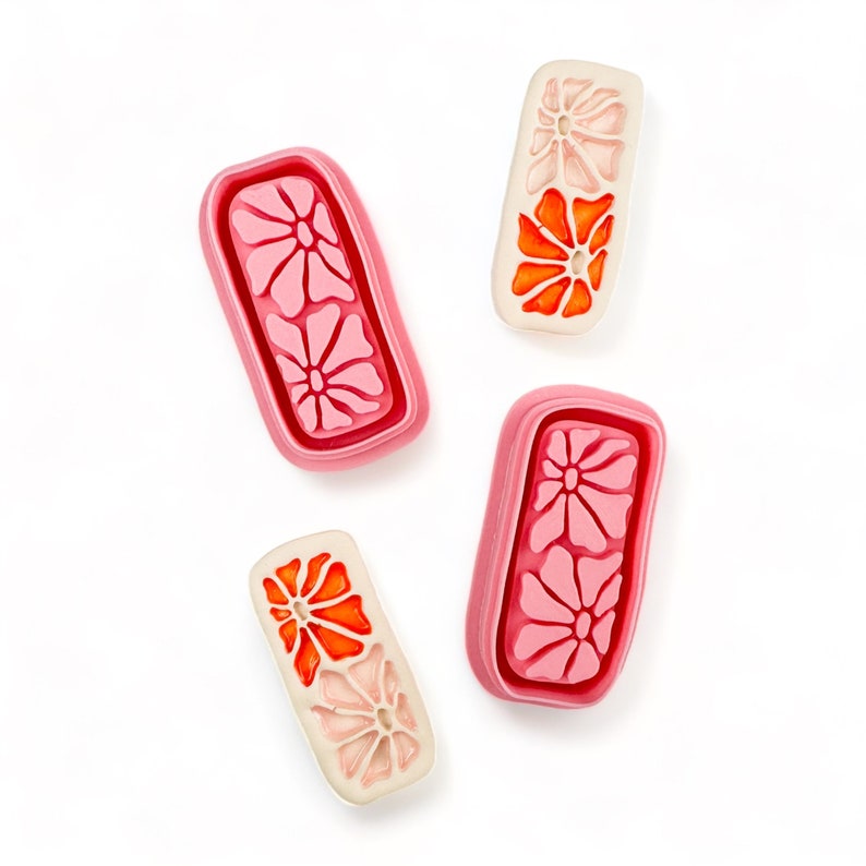 May include: Four pink and white rectangular ceramic tiles with floral designs. The tiles have a raised edge and a smooth surface. The flowers are in shades of pink and orange.