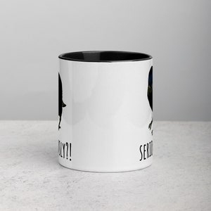 May include: White ceramic coffee mug with a black rim. The mug has a black and blue bird illustration on each side. The text "Seriously?!" is printed on the left side and "Seriously" is printed on the right side.