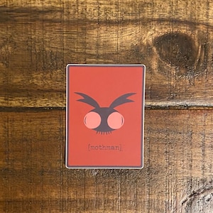 May include: Red sticker with a black silhouette of a mothman with large pink eyes. The text [mothman] is printed below the image.