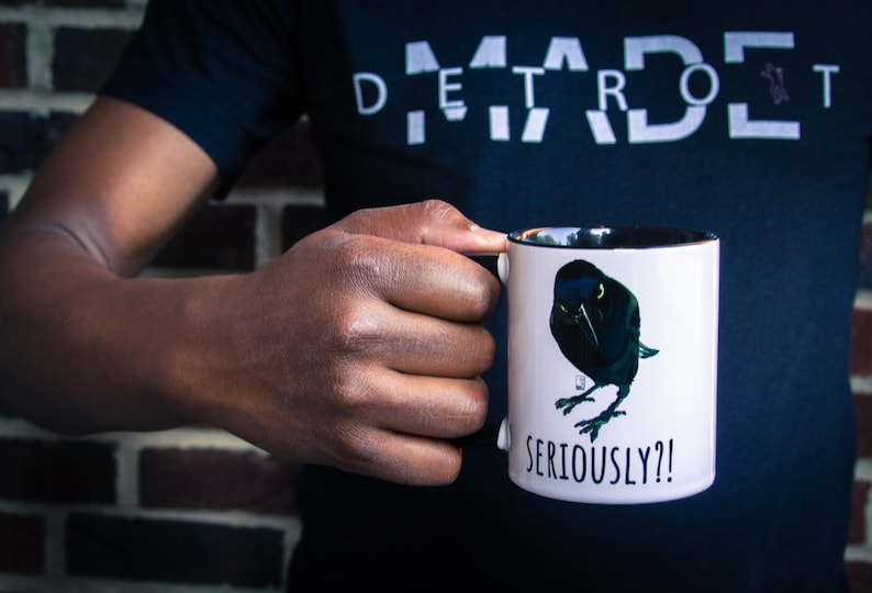 May include: White ceramic mug with a black rim and handle. The mug features a black and green illustration of a bird with the text "SERIOUSLY?!" printed below the bird.