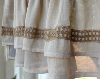 May include: A white tiered valance with a brown crocheted trim. The valance is made of a lightweight fabric and has a ruffled edge.
