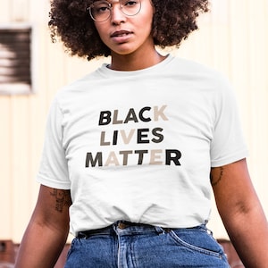 May include: A white t-shirt with the text "BLACK LIVES MATTER" printed in black and brown letters.