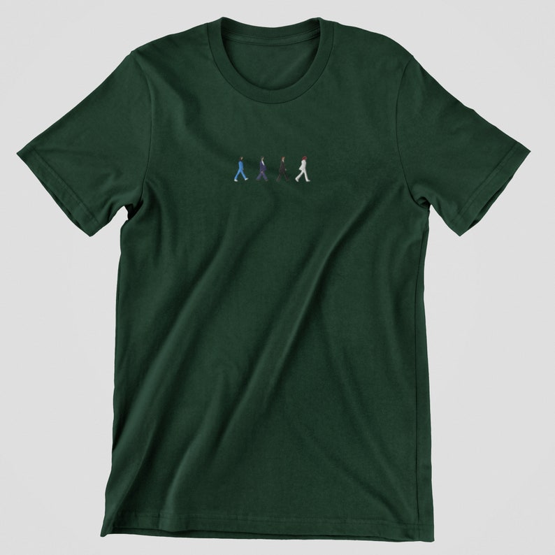 May include: A dark green t-shirt with a small embroidered image of four figures walking in a line. The figures are wearing different colored clothing.