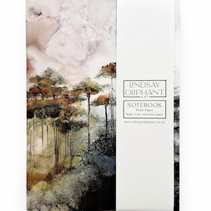 Op de afbeelding: Notitieboek met een landschapskunstprint met bomen in bruin, groen en goud. De kaft heeft een witte rug met de tekst "LINDSAY OLIPHANT ART" en "NOTEBOOK" met details over het papier.