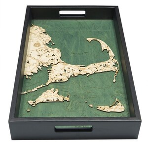 May include: A wooden serving tray with a raised map of Cape Cod, Massachusetts. The map is made of wood and has a green background. The tray is black and has two handles.