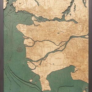May include: A detailed wooden map of Vancouver, British Columbia, with a green water color. The map shows the city's streets, rivers, and coastline. The map is framed in a dark wood frame.