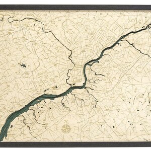 May include: A detailed wooden map of Philadelphia, Pennsylvania, with a blue river running through it. The map is framed in a dark wood frame.