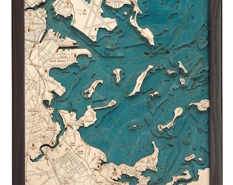 May include: A wooden map of Boston Harbour with a teal blue colour scheme. The map is framed in a dark brown frame. The map shows the coastline and islands of Boston Harbour, including the cities of Boston, Quincy, and Winthrop.
