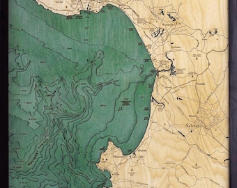 May include: A wooden map of Monterey Bay, California, with detailed contour lines showing the depth of the ocean. The map is framed in black and features the text "Monterey Bay, California" at the top.