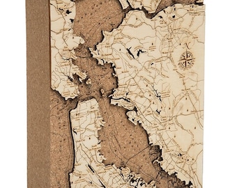 May include: A cork map of the San Francisco Bay Area, with the city names and surrounding towns labeled. The map is mounted on a wooden base and features a compass rose in the upper right corner.