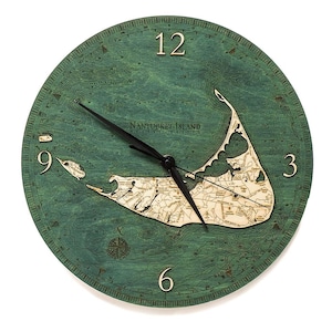 May include: A green wooden clock with a map of Nantucket Island, Massachusetts. The clock face features black hands and Roman numeral hour markers. The clock is 12 inches in diameter.