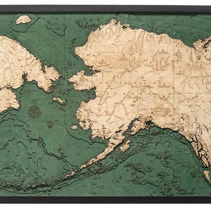 May include: A wooden map of Alaska with a green ocean and brown land. The map shows the state's coastline, rivers, and mountains. The map is framed in black.