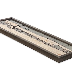 May include: A wooden wall art piece depicting a detailed map of a coastline. The map is framed in a dark wood frame and has a light wood background.
