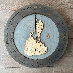 May include: A wooden tide clock with a map of Block Island, Rhode Island. The clock face is gray with white markings and the numbers 1 through 5. The clock hands are black. The clock is set to high tide.
