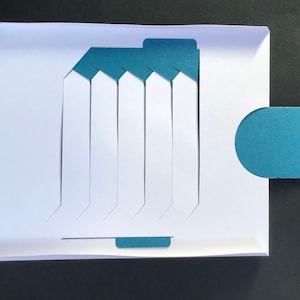 May include: A white card with a teal blue design. The card has seven vertical slots with a teal blue tab at the top and bottom. There is a teal blue semi-circle tab on the right side of the card.