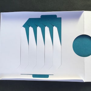 May include: A white card with a blue circle and a blue and white geometric design. The card is folded in half and has a flap on the front.