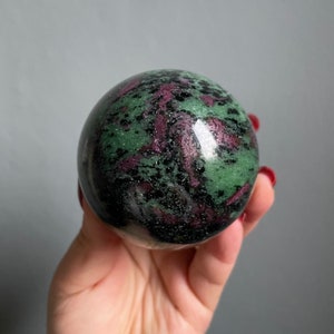 Op de afbeelding: Groene, zwarte en roze edelsteenkogel. De kogel is gepolijst en heeft een glad oppervlak.