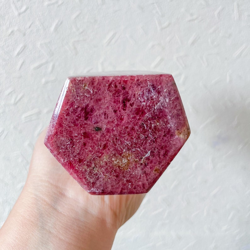 May include: A pink and red, faceted, hexagonal, polished ruby crystal.