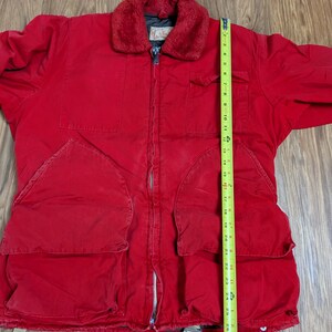 May include: A red jacket with a faux fur collar, multiple pockets, and a zipper closure. The jacket has a length of approximately 71 cm.
