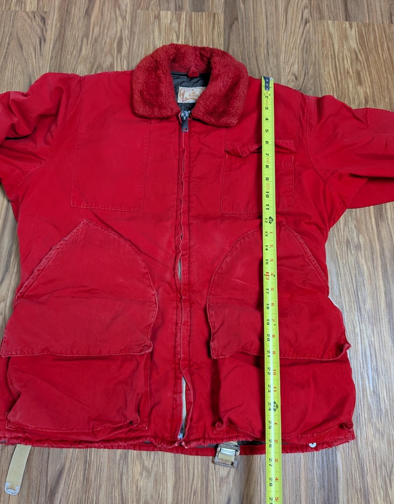 May include: A red jacket with a faux fur collar, multiple pockets, and a zipper closure. The jacket has a length of approximately 71 cm.