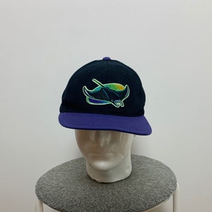 Peut inclure: Une casquette de baseball noire et violette avec un logo de raie pastenague vert, bleu et jaune brodé sur le devant.